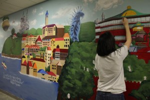 Serafina Urrutia | Hawkeye Senior Kyra Dahlman works on a mural that adorns the walls of the art hallway. 